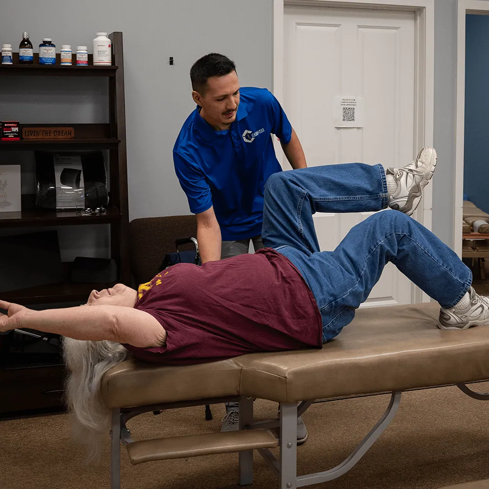 Chiropractor guiding a patient through a hip stretch