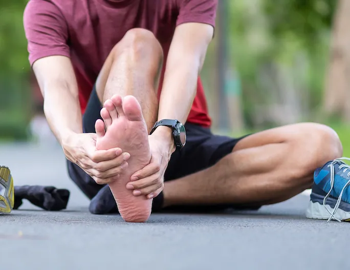 man holding his foot due to plantar fasciitis pain