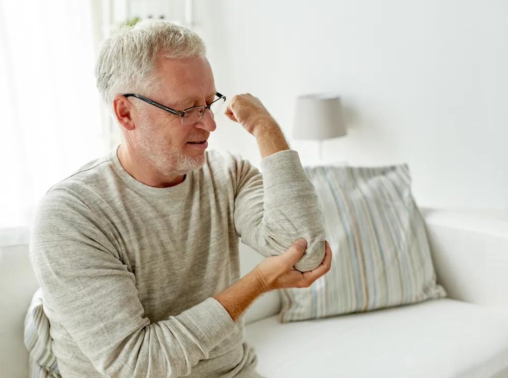 old man holding his elbow due to pain